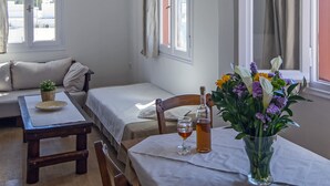 Ein gemütliches Zimmer mit Esstisch für zwei Personen, einer Bank und einem Fenster mit Vorhängen.