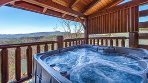 A hot tub with controls, wooden deck, and a view of mountains. - Royal Vista Lodge (Sevierville)