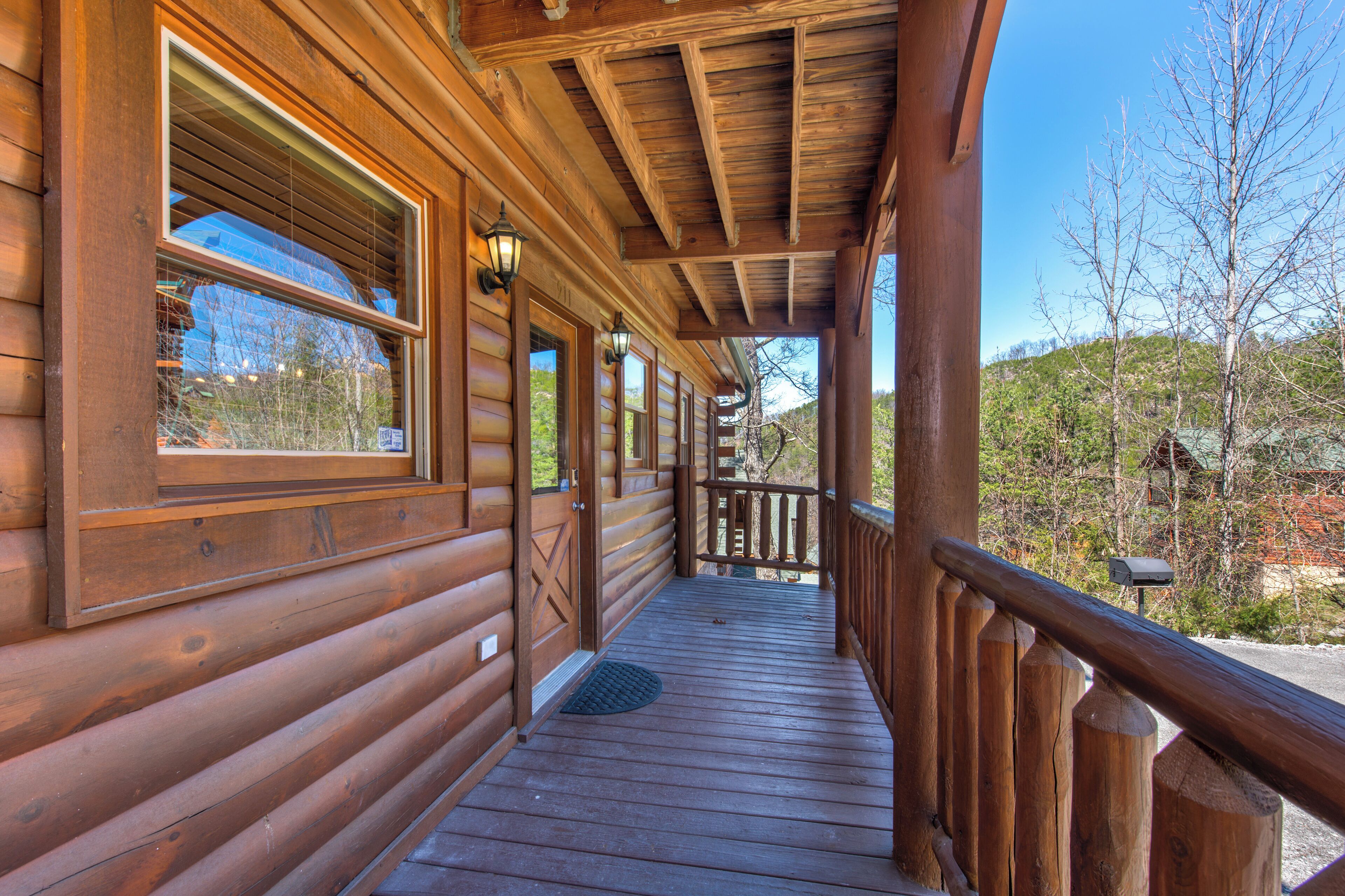 A wooden cabin with a covered porch, large windows, and a mailbox.