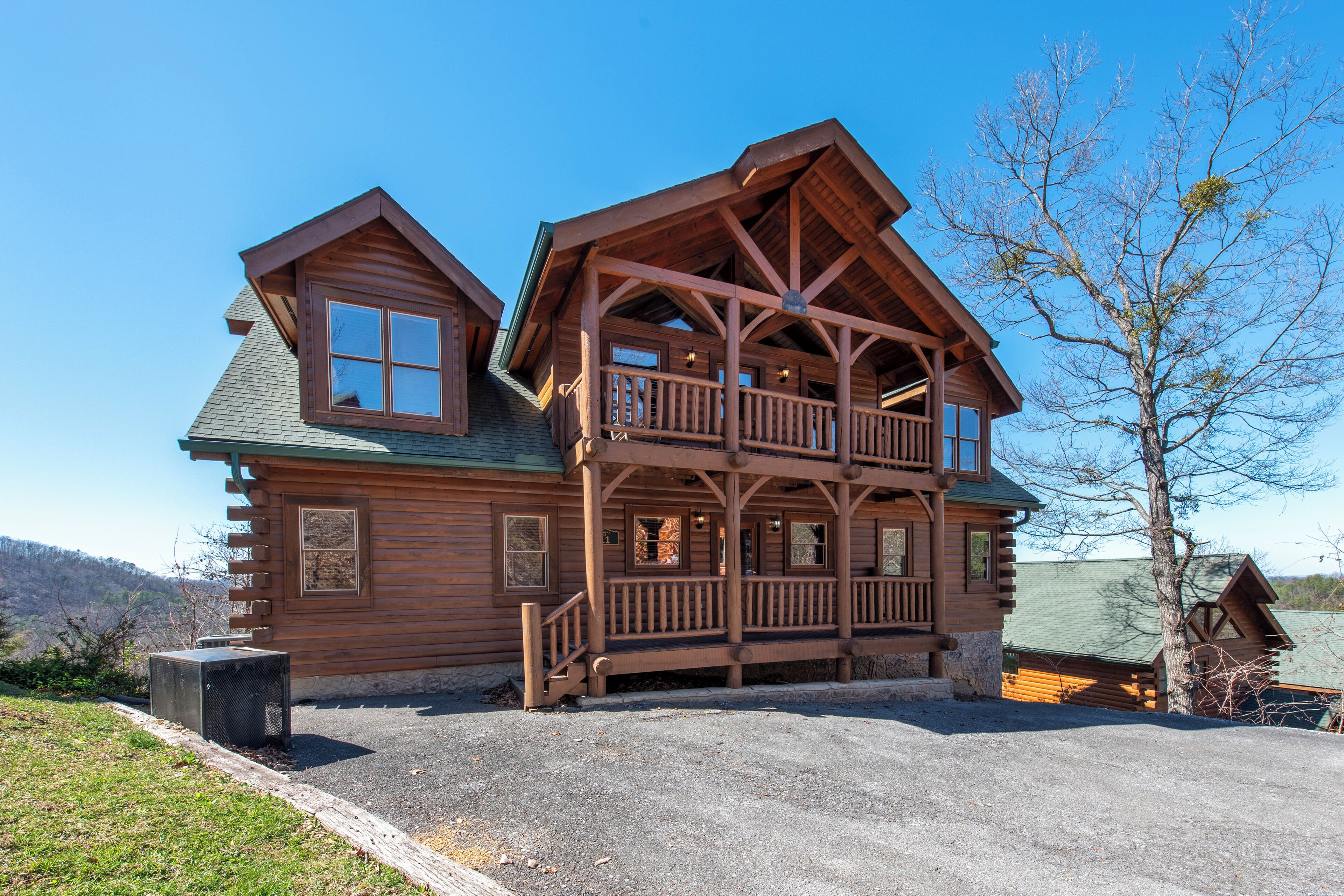 A log cabin with a two-story balcony, a covered porch, and a stone foundation.