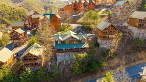 A lodge with multiple wooden buildings, each with a distinct roof style and surrounded by trees. - Royal Vista Lodge (Sevierville)