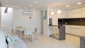 Un apartamento moderno con comedor, cocina y una escalera que sube a un piso superior.