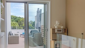 Un apartamento moderno con un ventanal corredizo que da a un balcón con mobiliario exterior.