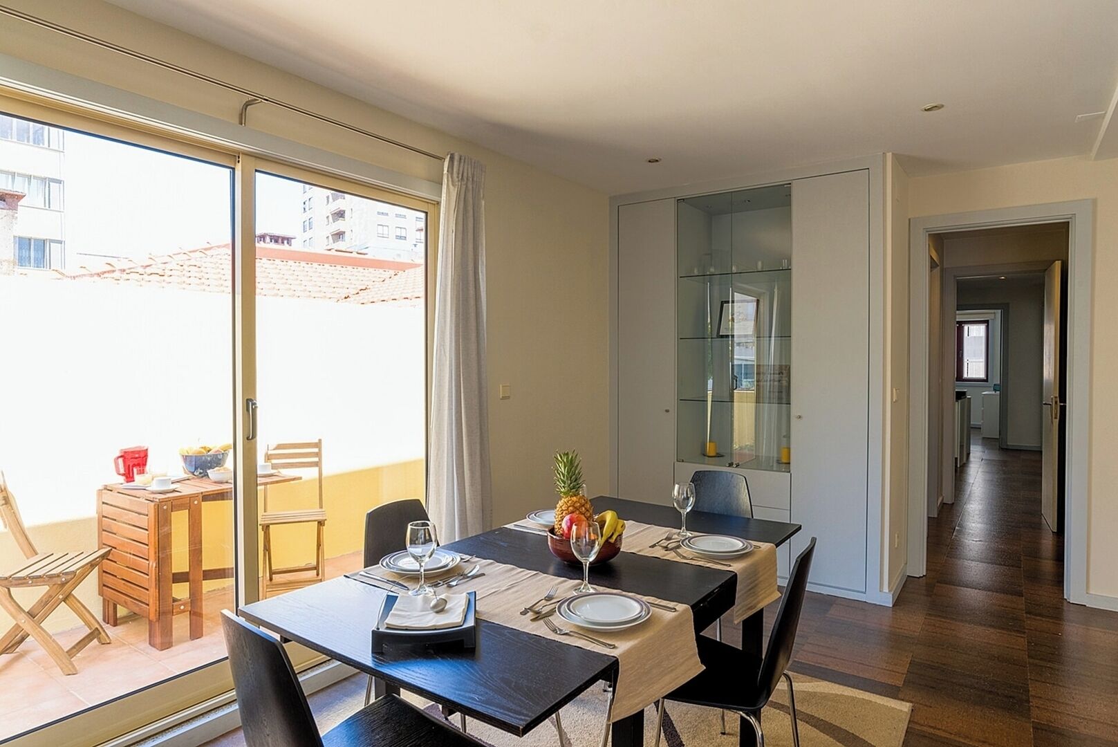 Ein Essbereich mit Tisch für zwei Personen, einer Glasvitrine und Blick auf den Außenbalkon.