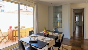 A dining area with a table set for two, a glass cabinet, and a view of the outside balcony. - Porto Gaia City House (Vila Nova de Gaia)