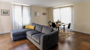 A modern living room with a grey sectional sofa, a dining table with chairs, and a wooden floor. - Porto Gaia City House (Vila Nova de Gaia)
