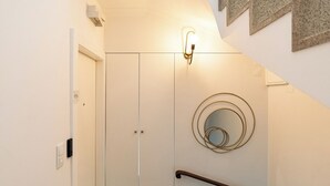 A modern interior with a glass door leading to a room, a wall-mounted light fixture, and a spiral mirror. - Lu | Localização Central, Vista Rio and Nespresso (Vila Nova de Gaia)