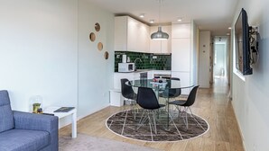 A modern apartment with a dining area featuring a glass table and black chairs, a kitchenette with green tiles, and a grey sofa in the living area. - Lu | Localização Central, Vista Rio and Nespresso (Vila Nova de Gaia)