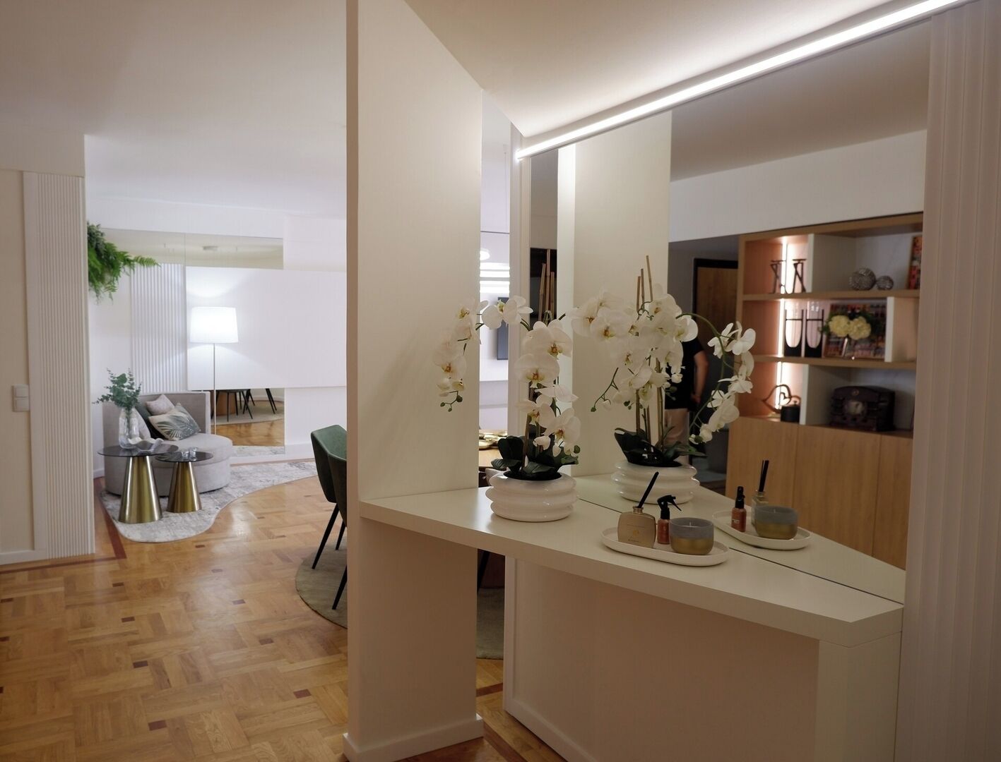 Ett modernt vardagsrum med en vit soffa, ett soffbord och en matplats med en lampa.