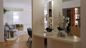 Een moderne woonkamer met een houten vloer, een bank, een salontafel, en een eethoek met stoelen.