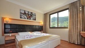 Een hotelkamer met een groot bed, een hoofdeinde, een nachtkastje, gordijnen voor het raam en een schilderij aan de muur.