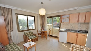 Een knus woongedeelte met een bank, een kleine tafel, een eethoek en een kitchenette.