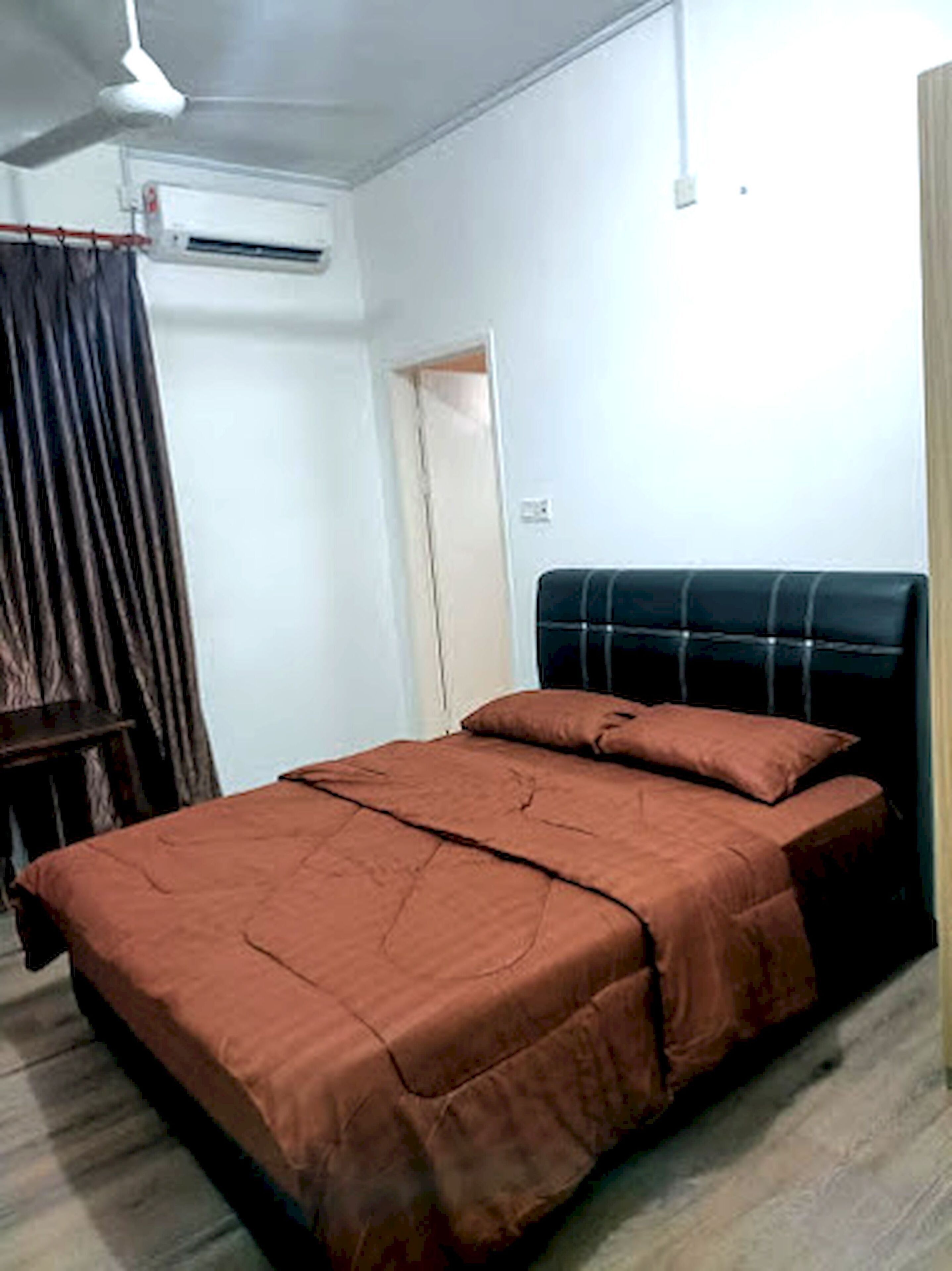 A bedroom with a bed, a ceiling fan, and a door.