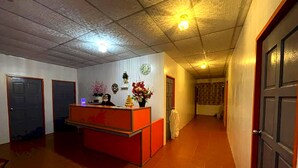 A reception area with a red counter, a clock on the wall, and a door on the right. - OYO HOME 90768 Flo Inn Motel (Tawau)