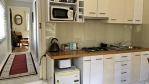 Une cuisine moderne avec des meubles blancs, un four à micro-ondes, une bouilloire et une cuisini ère à gaz.