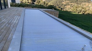 Een modern terras buiten, met een metalen hekwerk en een stenen muur.