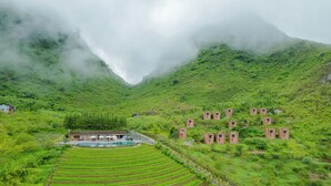 A terraced rice field with a pool and a small building with a red roof. - H'mong Village Resort Ha Giang (Lung Tam)