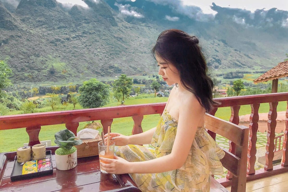 A person seated at a table with a view of a mountainous landscape.