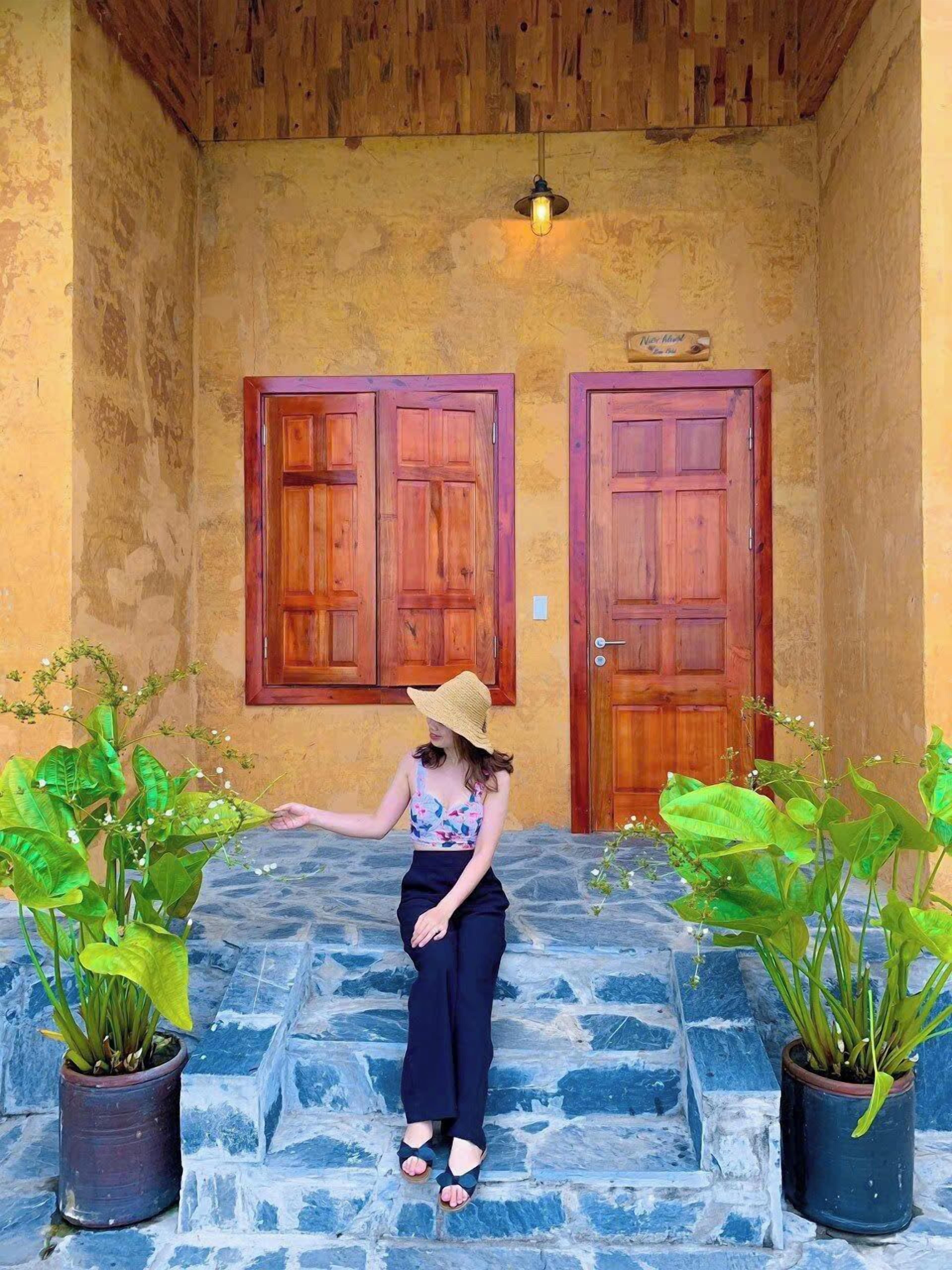 A person standing on stone steps in front of two wooden doors with a light fixture above.