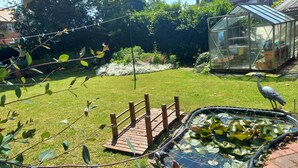 A garden with a pond, a wooden bridge, and a greenhouse. - Charming 4-bed Victorian House in Retford (Retford)