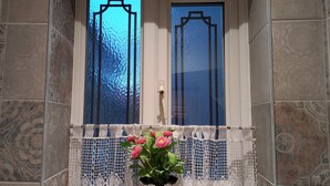 A bathroom with patterned tiles, a window with a decorative frame, and a potted plant with pink flowers. - Charming 4-bed Victorian House in Retford (Retford)