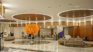 A spacious lobby with a marble floor, a central orange tree, and modern lighting fixtures. - Helnan Hotel Port Fouad (Port Fuad)