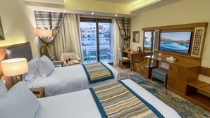 A hotel room with two beds, a desk, a television, and a view of the city. - Helnan Hotel Port Fouad (Port Fuad)