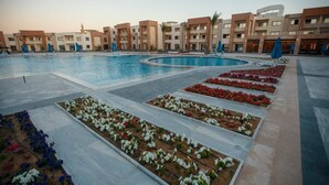 A swimming pool surrounded by flower beds and modern buildings with balconies. - Helnan Hotel Port Fouad (Port Fuad)