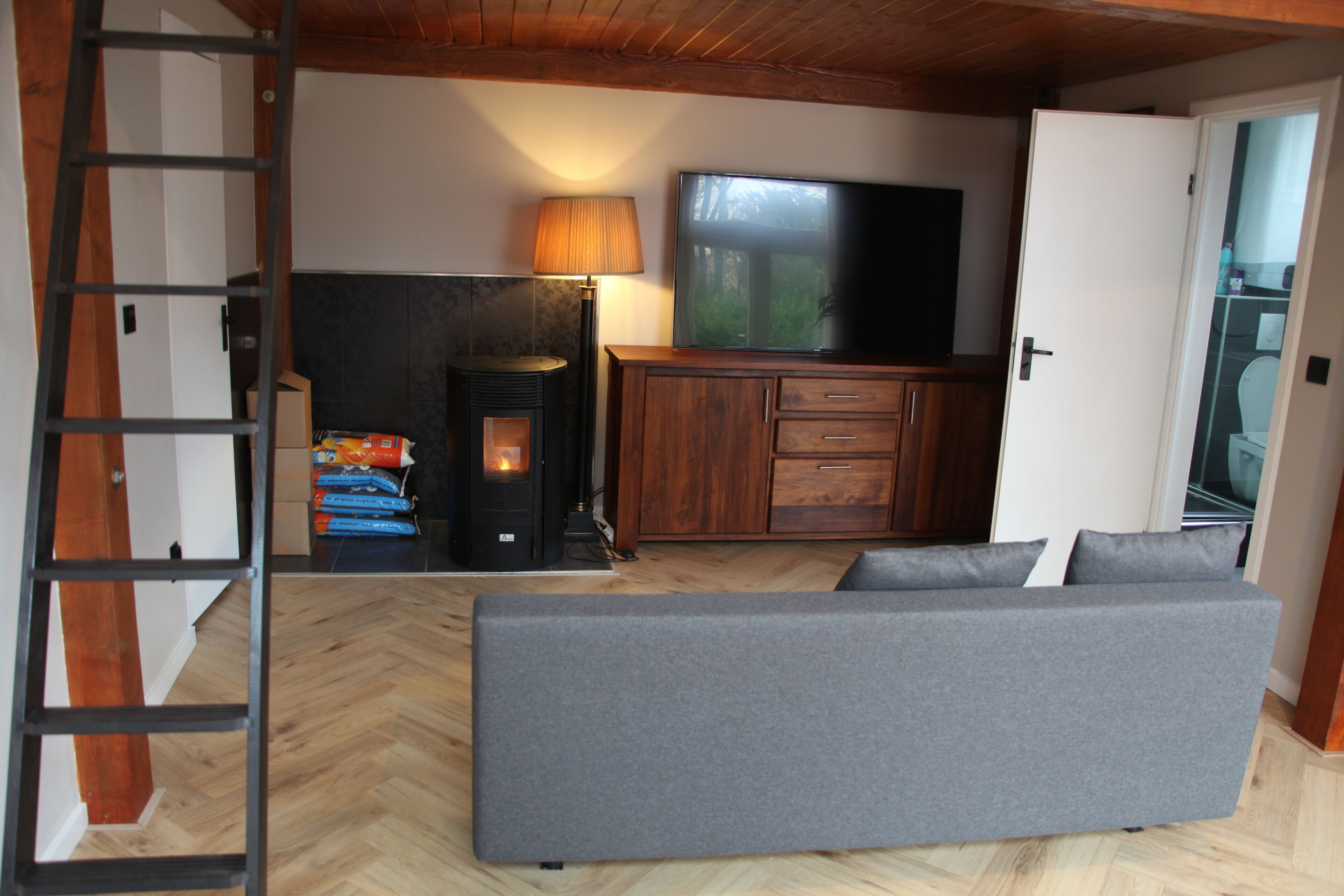 Una sala de estar acogedora con un sofá, televisión, chimenea y un mueble de madera.