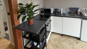 Moderni keittiö, jossa on valkoiset kaapit, musta työtaso ja ruukussa oleva kasvi.