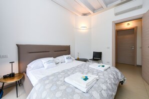 A hotel room with a large bed, a bedside table, a chair, and a door.