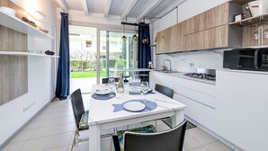 Una cocina moderna con armarios blancos, microondas integrado y comedor con mesa lista para dos.