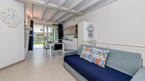 Una sala de estar moderna con un sofá gris, un comedor y una cocina.