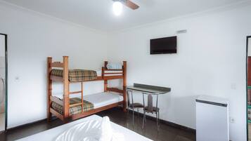 Quarto com beliche, escrivaninha, cadeira e um pequeno frigorífico.