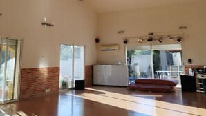 A spacious room with a high ceiling, wooden beams, a large window, and a sliding glass door leading to an outdoor area. - LOFT 100m2 (Aubord)