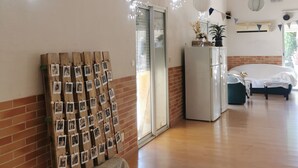 A spacious room with a wooden floor, a refrigerator, a bed, and a wall decorated with pictures and string lights. - LOFT 100m2 (Aubord)