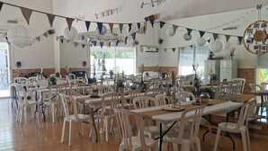 A spacious dining area with white plastic chairs and tables, wooden beams on the ceiling, and string lights. - LOFT 100m2 (Aubord)
