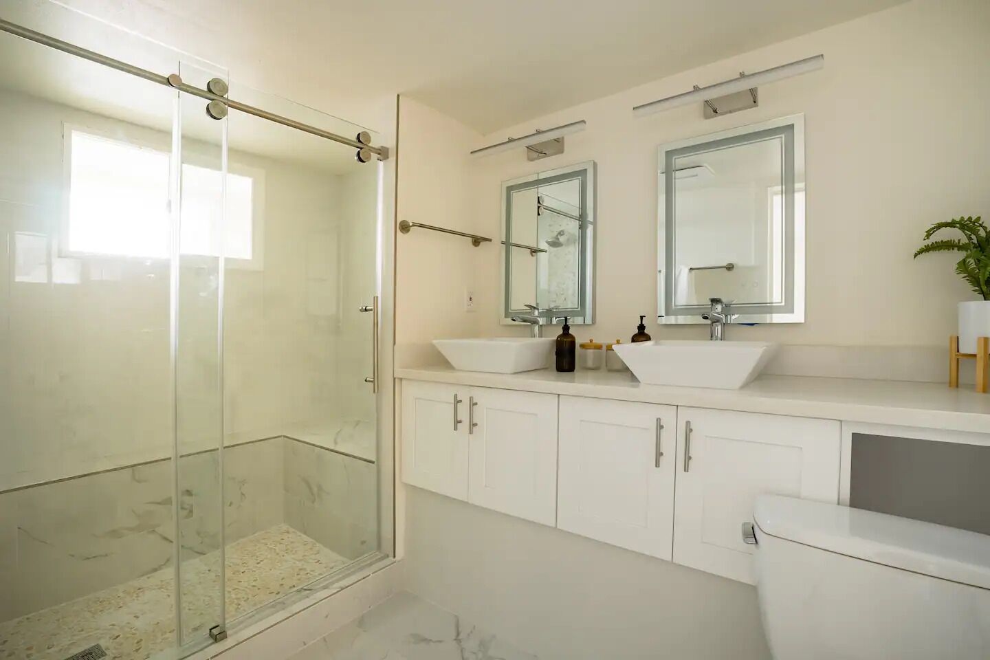 Un bagno moderno con box doccia in vetro, due lavabi e un water.