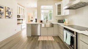 Una cocina moderna con armarios blancos, electrodomésticos de acero inoxidable y un amplio ventanal que aporta luz natural.