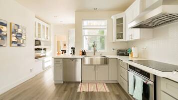 A modern kitchen with white cabinetry, stainless steel appliances, and a large window providing natural light.