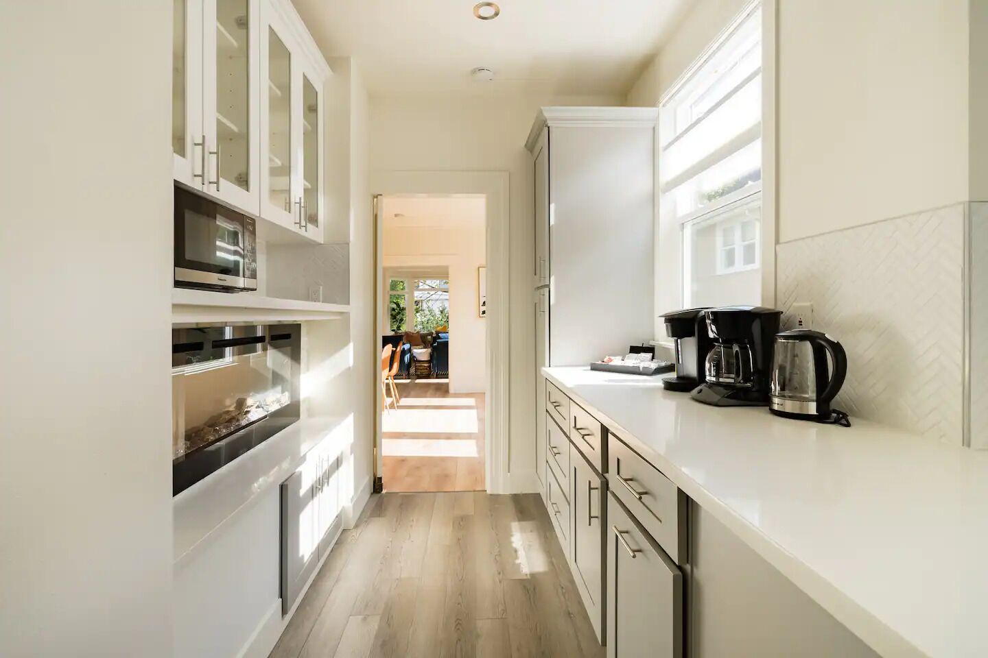 Una cocina moderna con armarios blancos, horno empotrado y espacio para café.