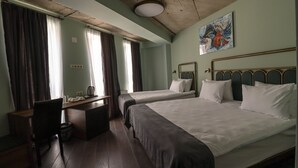 A hotel room with two beds, a desk, and a chair. - Paliani Hotel (Mestia)