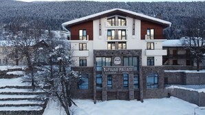 A hotel with a modern design, featuring a prominent entrance with a sign, multiple windows, and a stone facade. - Paliani Hotel (Mestia)