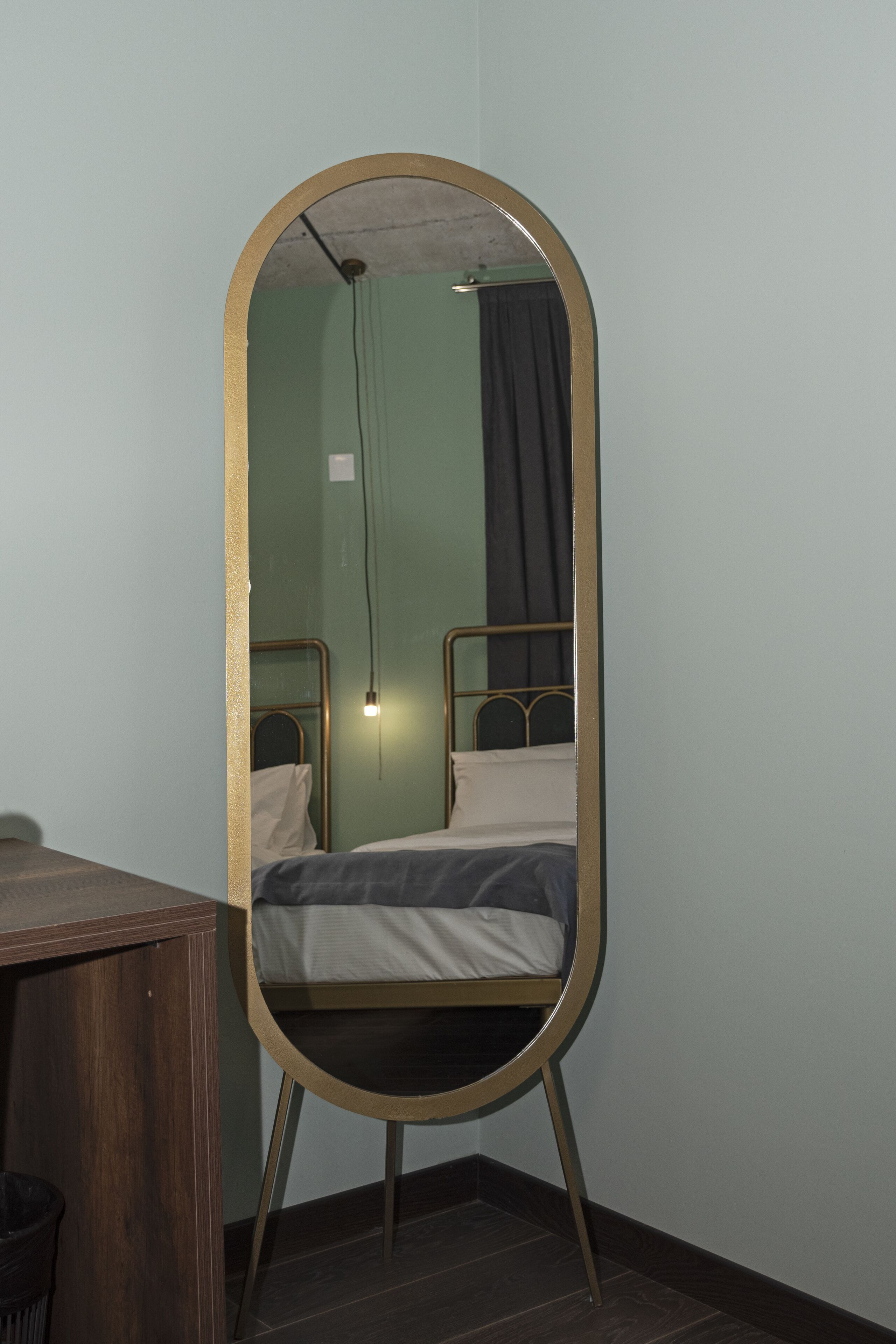 Une chambre avec un lit, un bureau et un miroir doté d’un cadre doré.