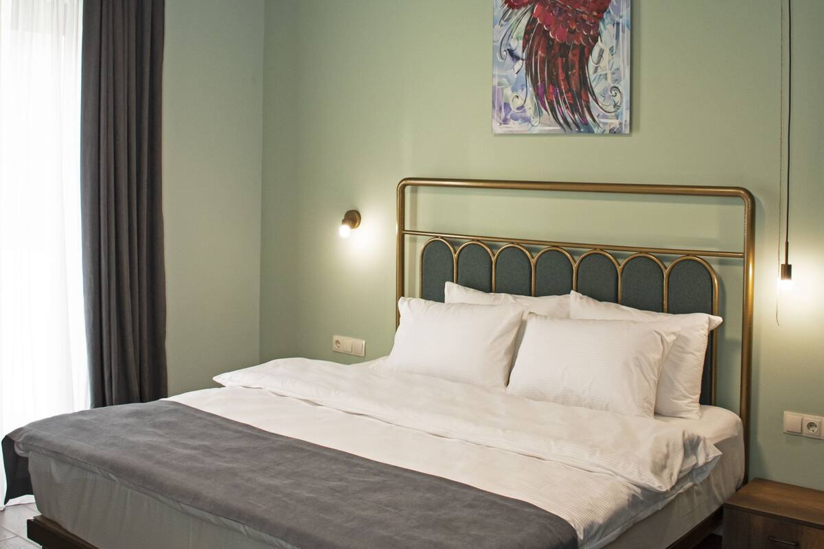 Ein Schlafzimmer mit einem Bett, einem Gemälde, einer Pendelleuchte und einem Nachttisch.