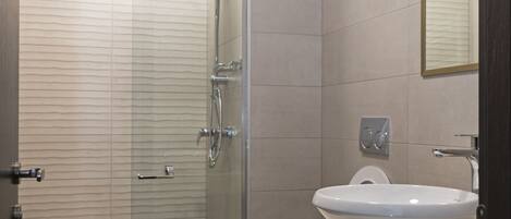 Un baño moderno con ducha de vidrio, lavamanos blanco y un inodoro.
