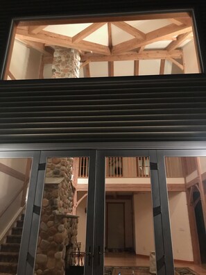 Experience a spacious atmosphere with high ceilings and a rustic touch, featuring a dining area and glass doors leading to a multi-level layout.