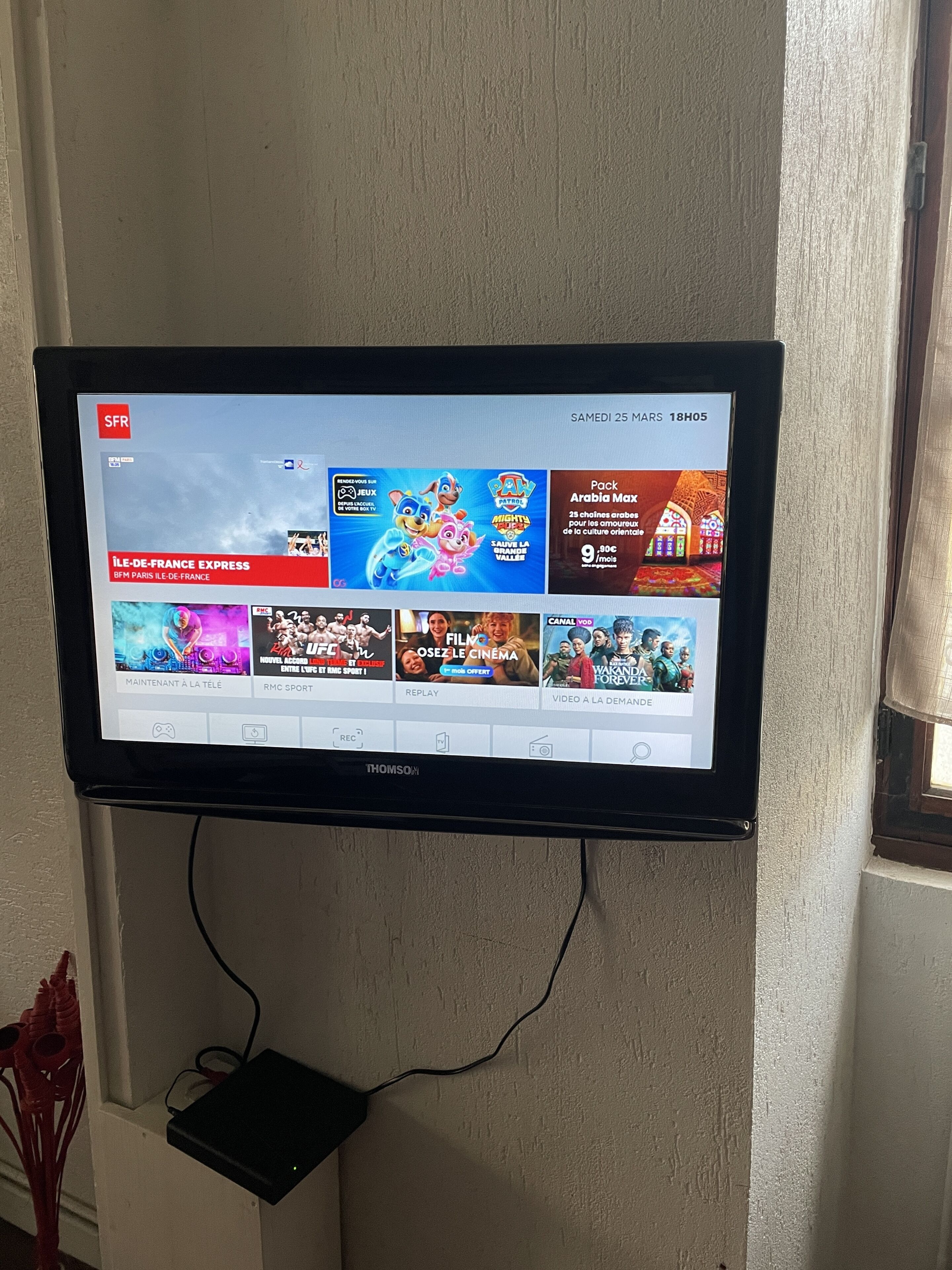 A flat-screen TV mounted on a wall displaying a streaming service interface with various content options.