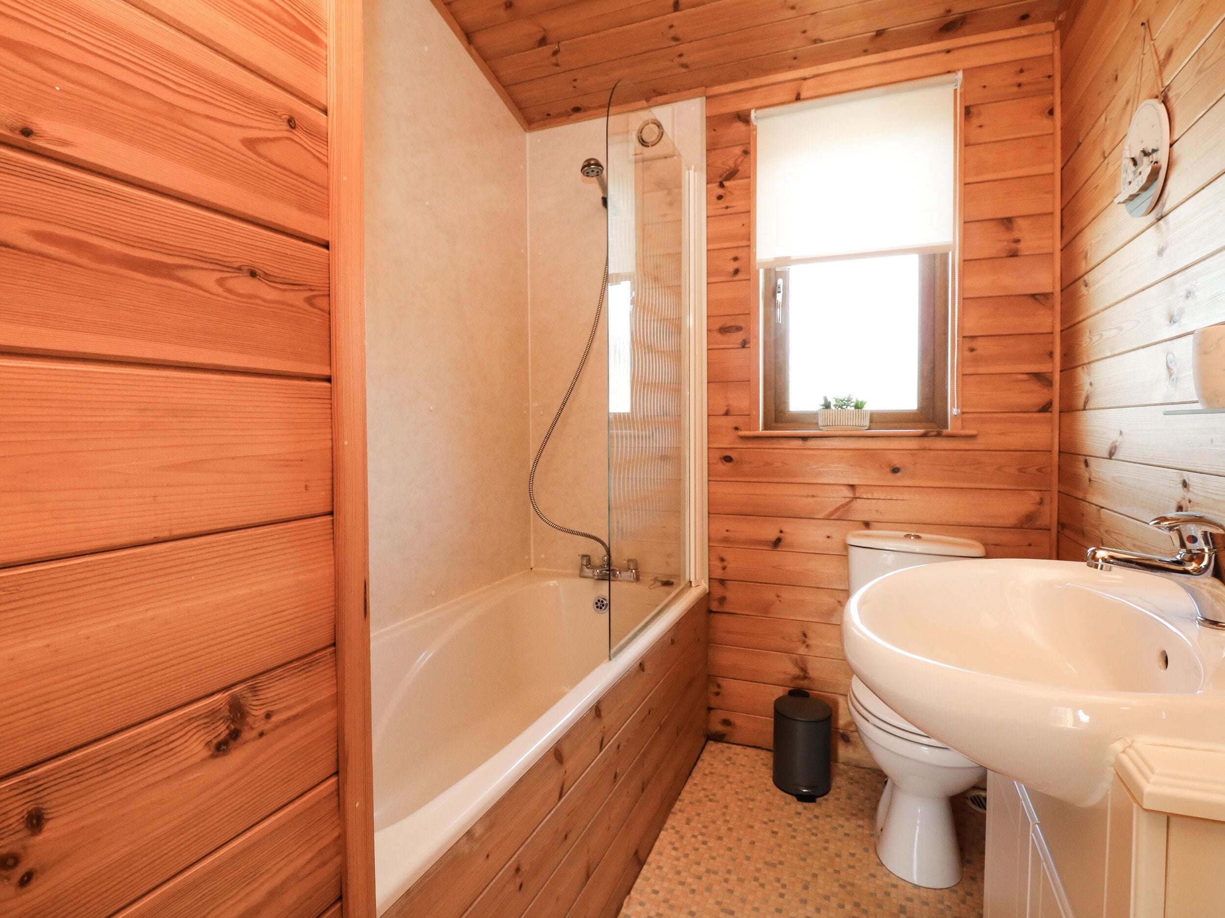 Baño de cabaña de madera con bañera, inodoro y lavamanos.