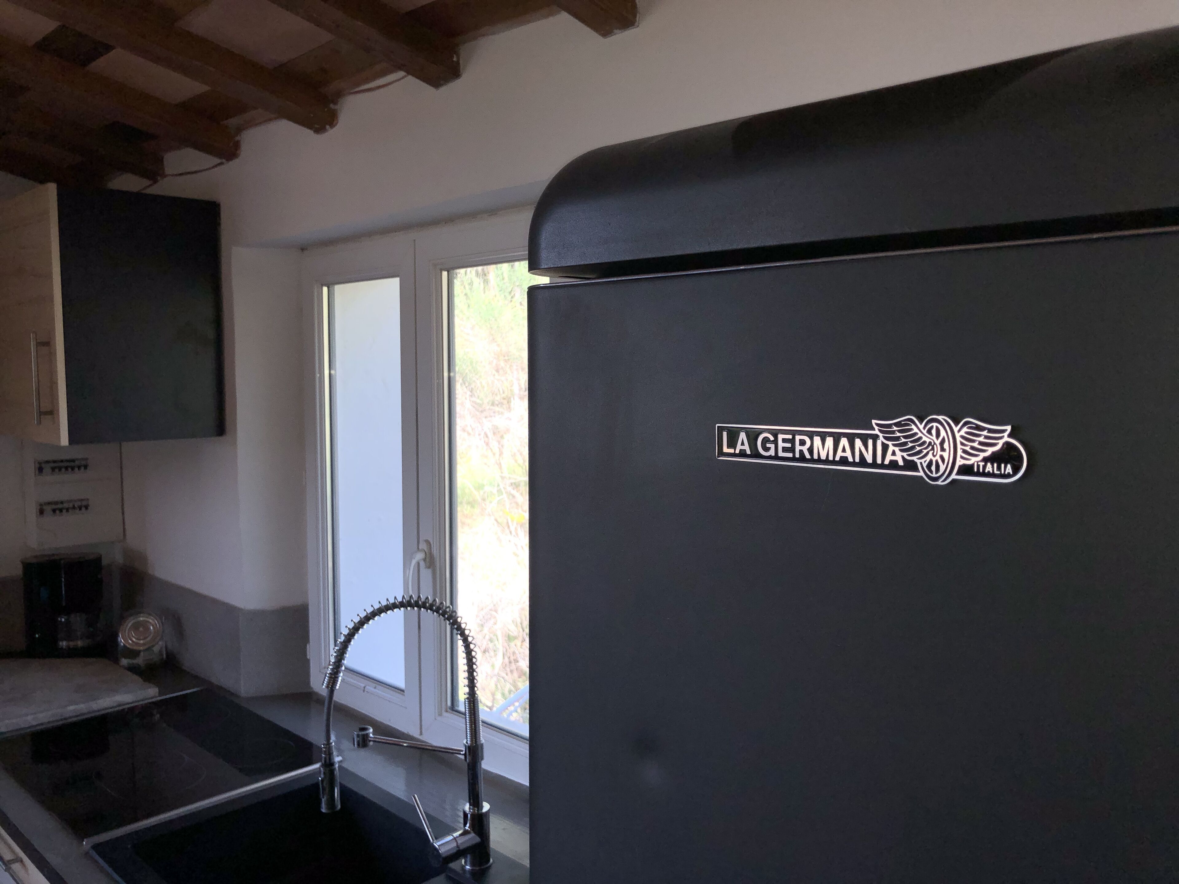 A kitchen with a black refrigerator, a window, and a sink.
